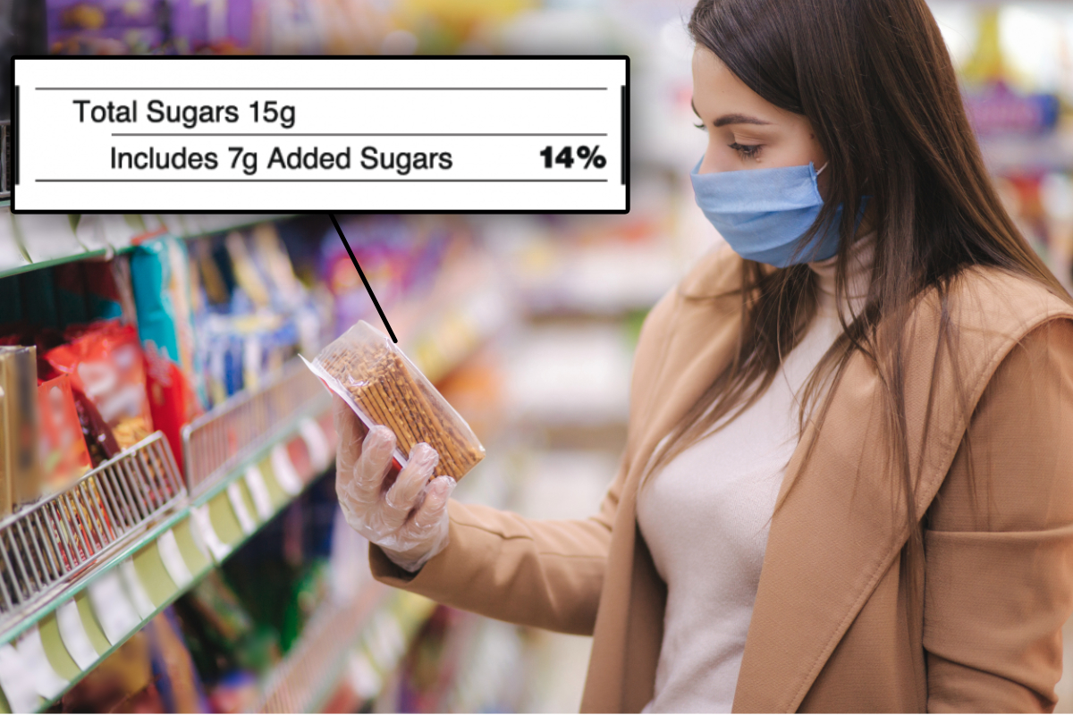 Woman reading added sugars label on crackers in supermarket