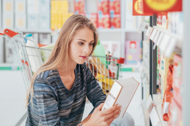 Woman reading ingredients panel on packaged food