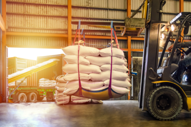 Forklift handling sugar bag for stuffing into container for export.