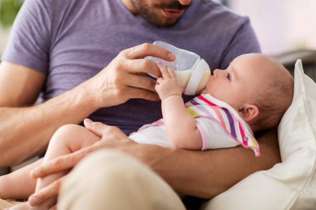 Man giving a baby formula from a bottle