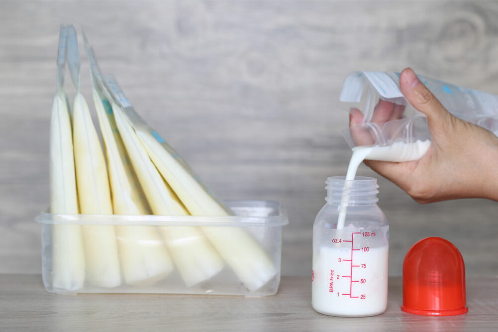 Woman pouring milk into bottles for a baby